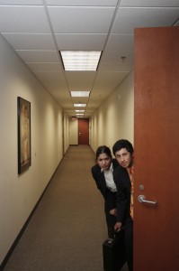 two workers hiding behind office door
